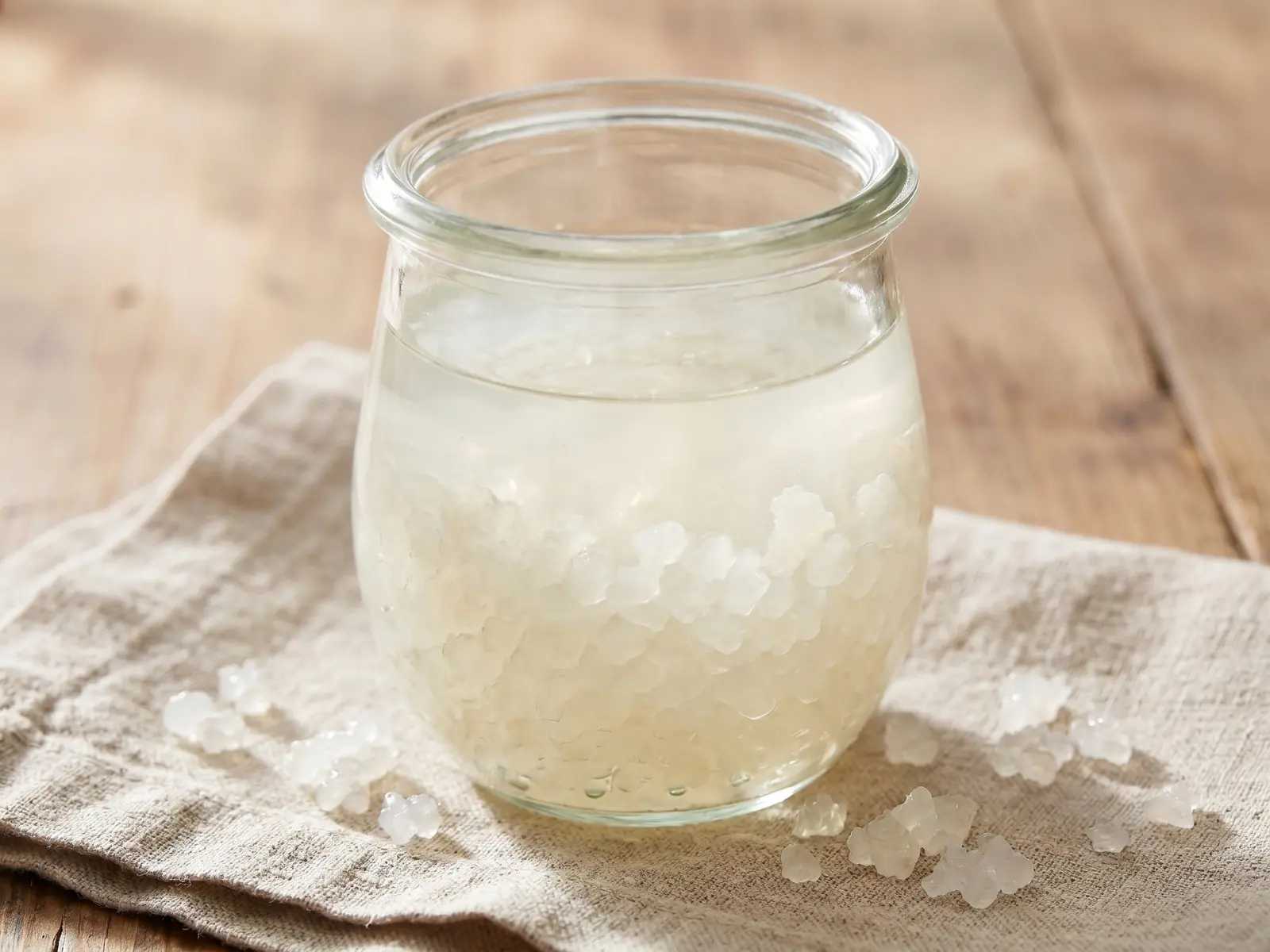 tibicos de agua Frasco de kefir de água sobre linho cru, com grãos translúcidos em repouso no líquido